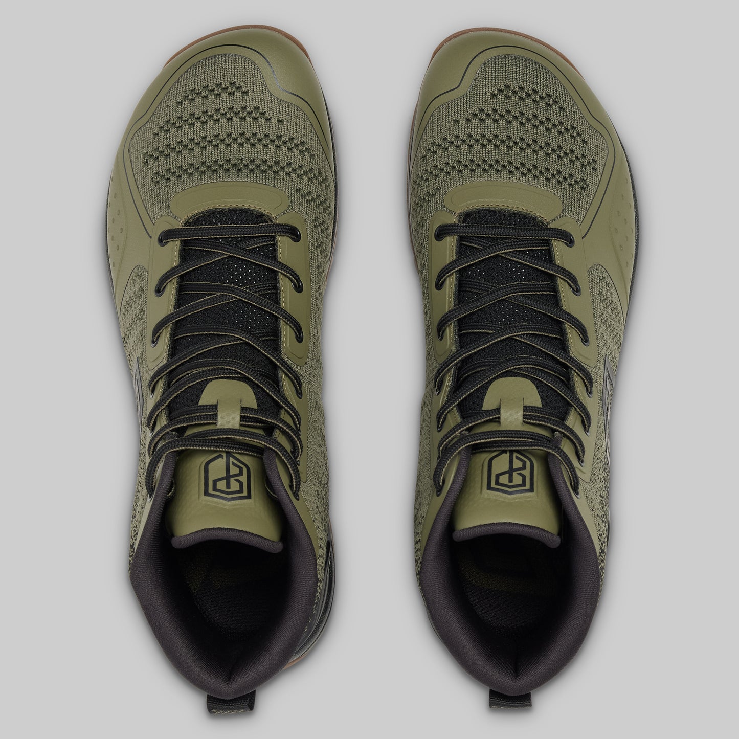 Pair of green athletic shoes with black laces on a light gray background