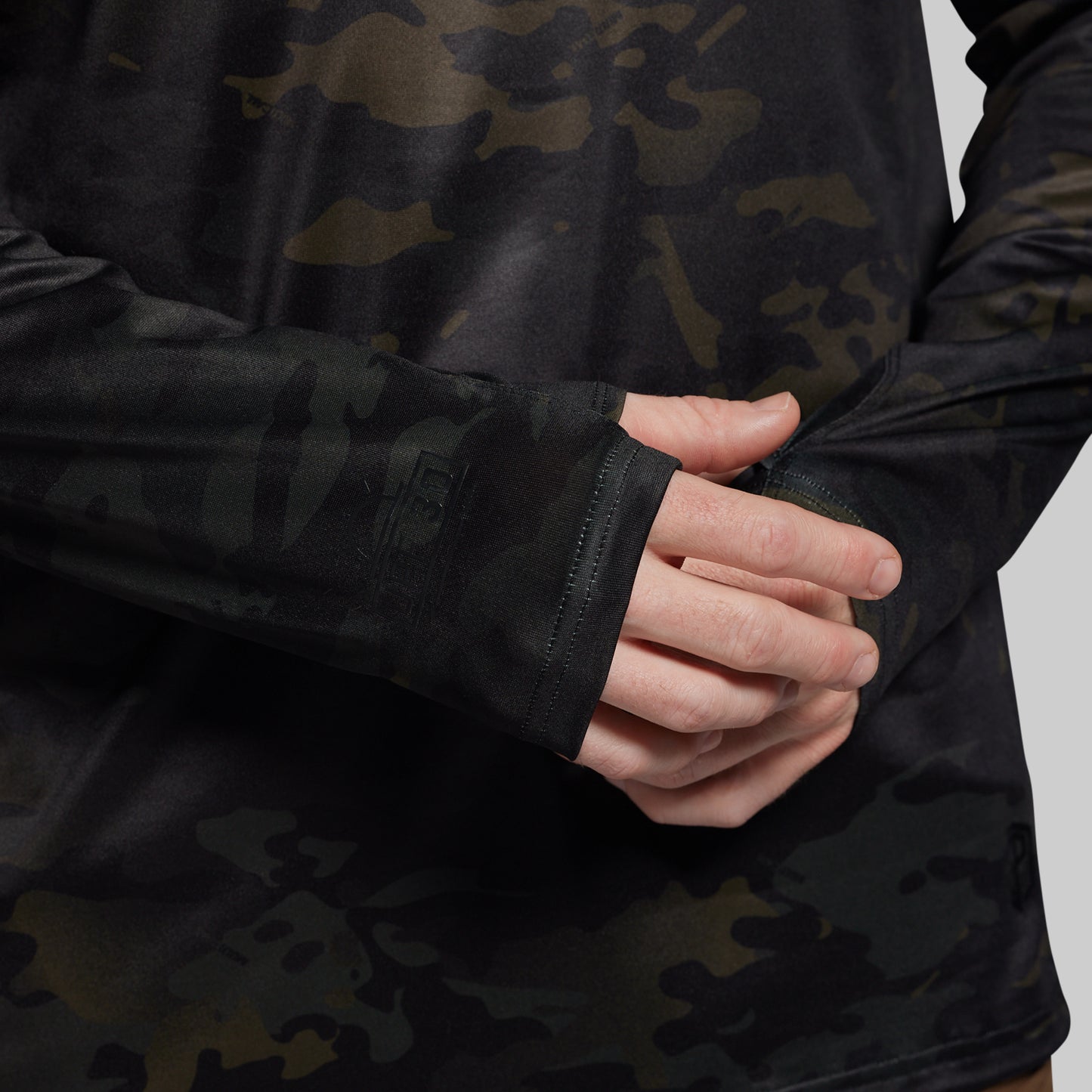 Person wearing a black camouflage sun shirt with a close-up of the sleeve and hand.