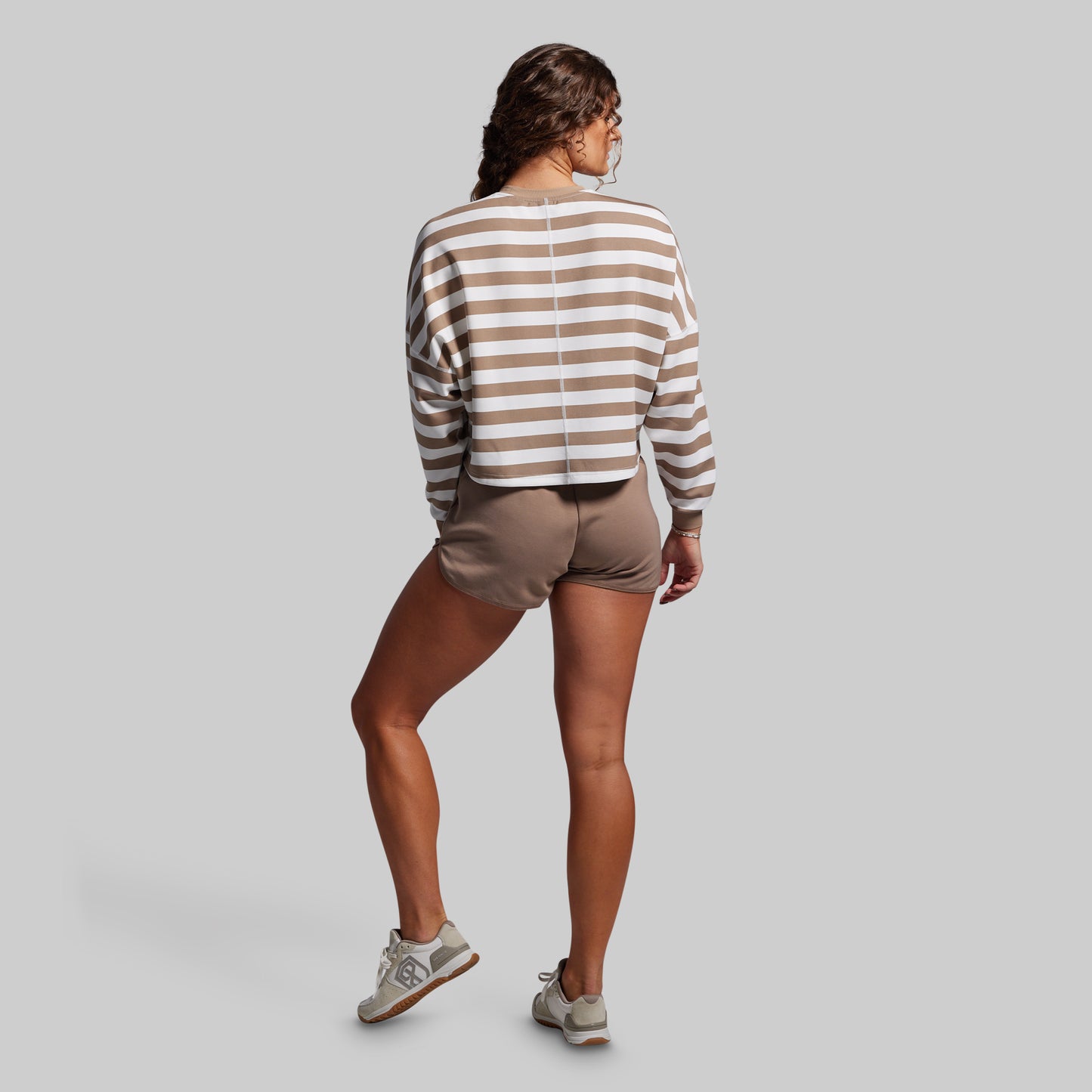 Person wearing a striped sweater and shorts on a plain background