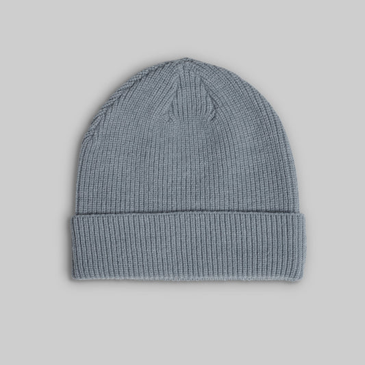 A light blue-gray ribbed knit beanie hat with a folded cuff, shown against a solid gray background.