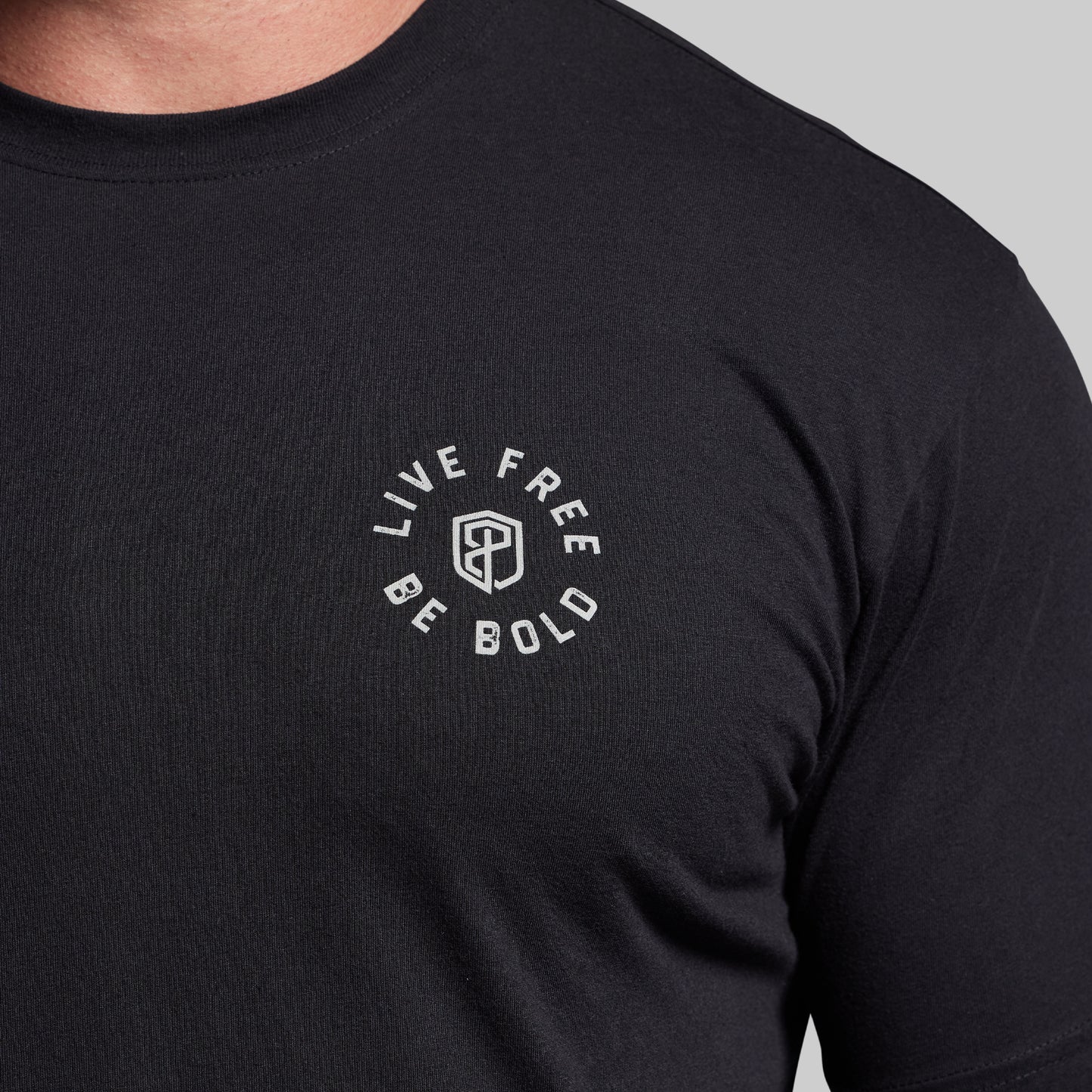 Black t-shirt with 'Live Free Be Bold' text on a gray background