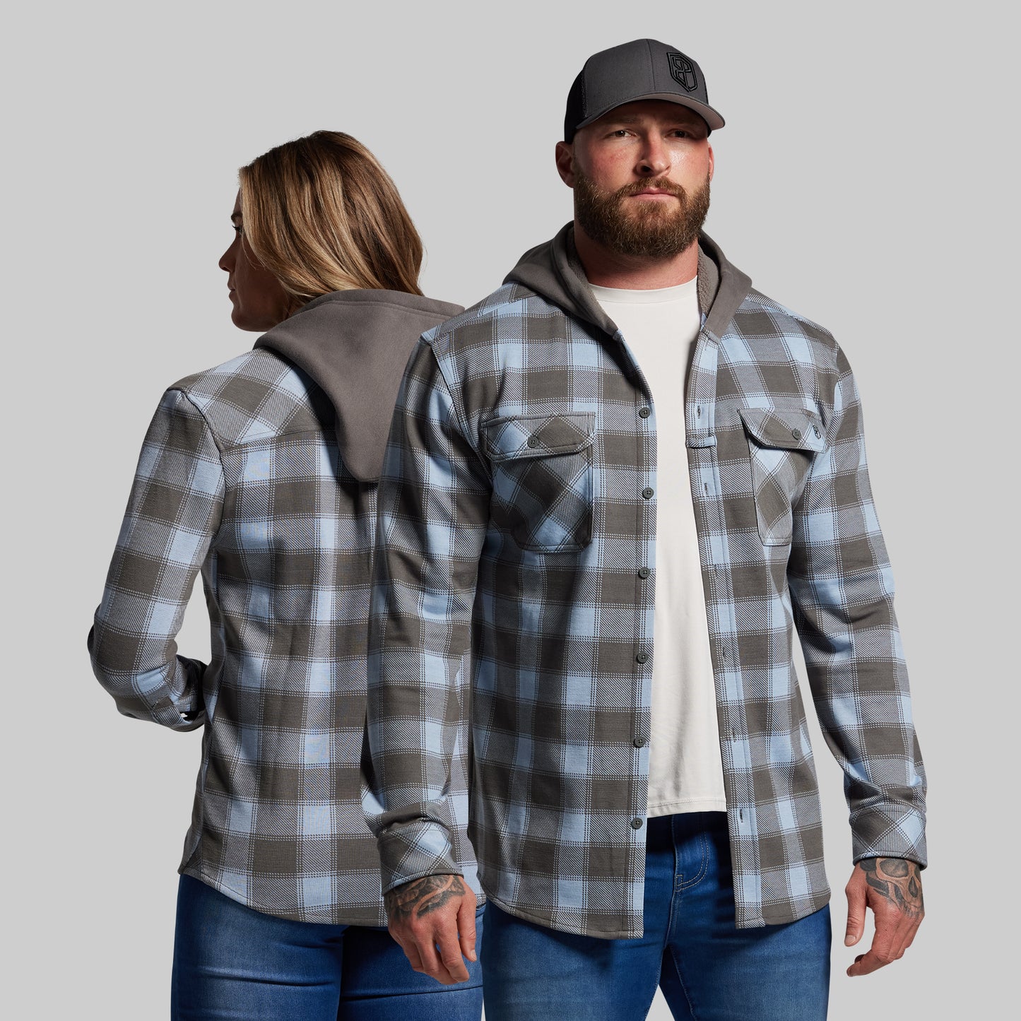Two people wearing plaid shirts against a plain background