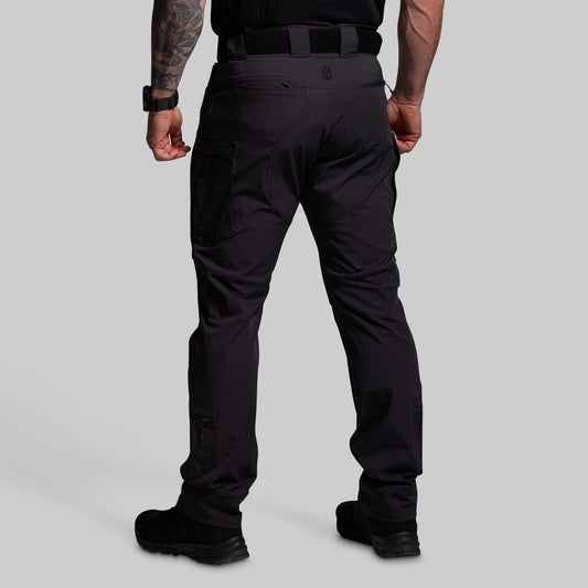 Person wearing black tactical pants on a gray background