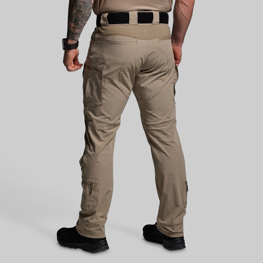 Person wearing beige tactical pants on a gray background