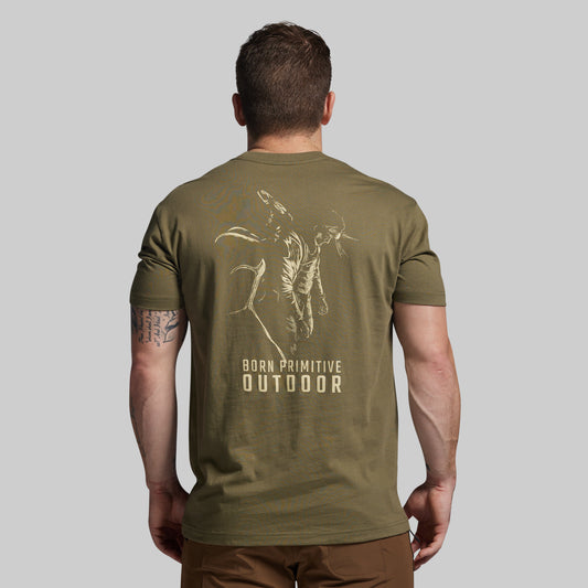 Man wearing an olive green t-shirt with a graphic design and text on the back, on a plain background.