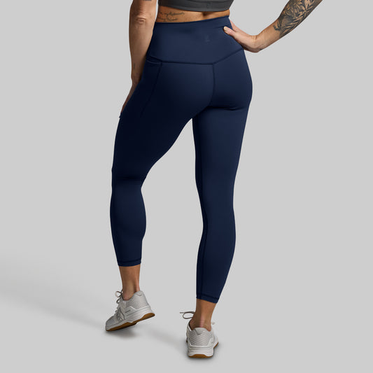 Person wearing navy blue leggings on a gray background