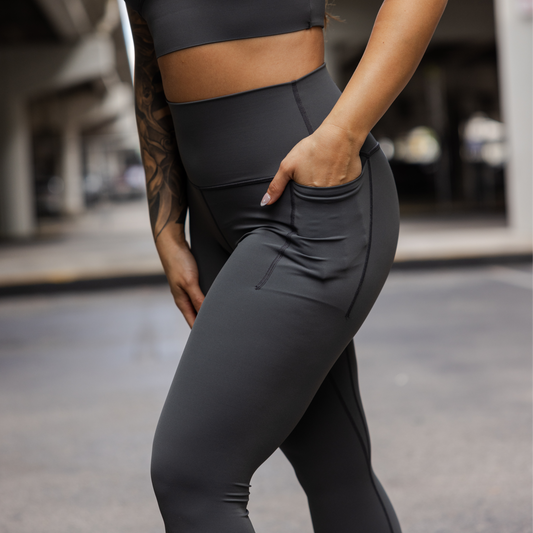 Person wearing a pair of dark gray leggings with hand in pocket