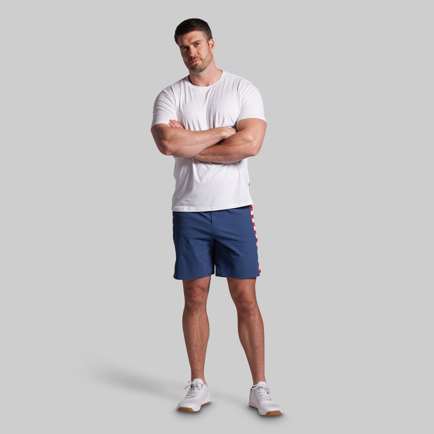 Man wearing a white t-shirt and blue shorts on a gray background