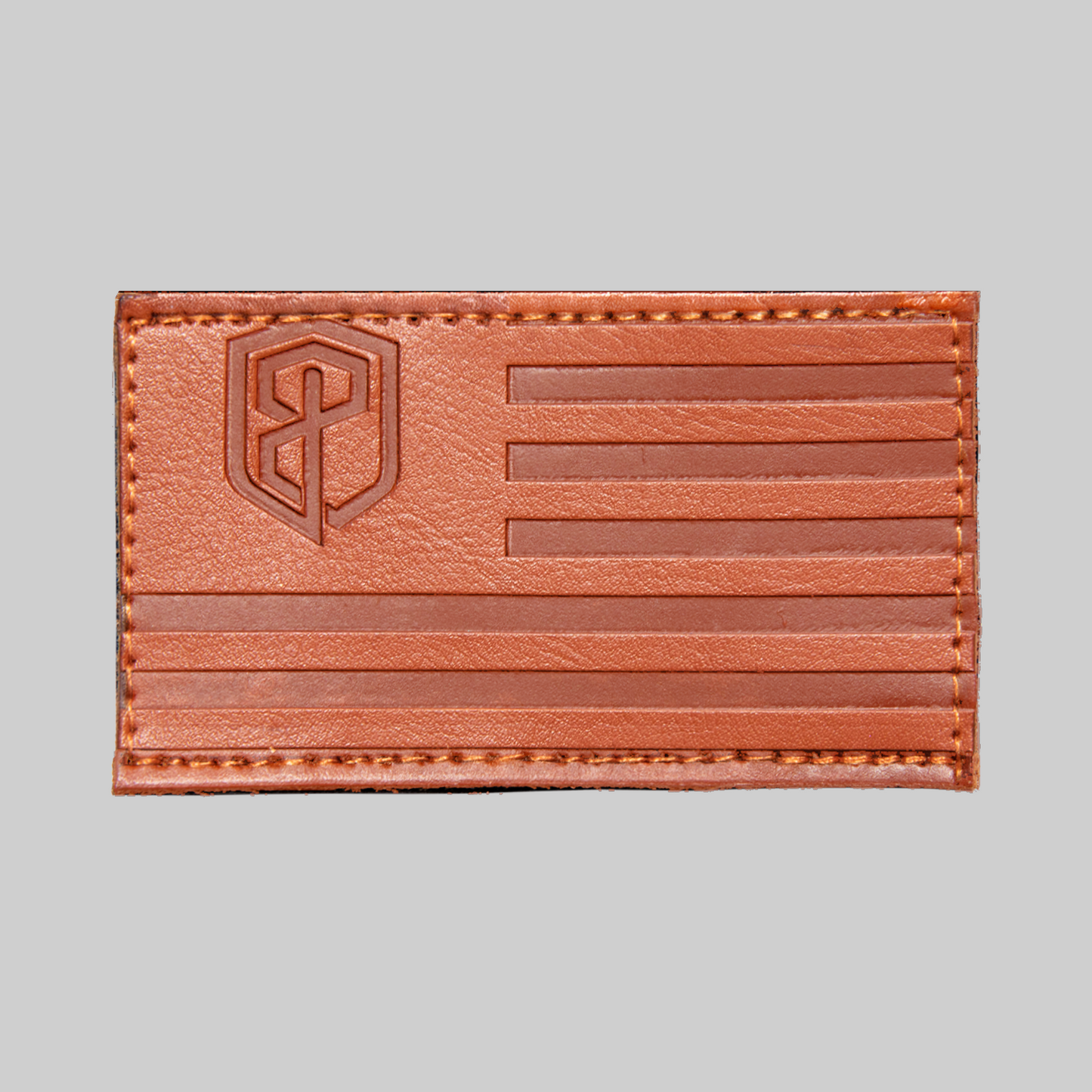 Brown leather patch with American flag design and logo on a gray background