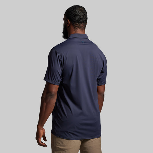Person wearing a navy blue polo shirt against a plain background