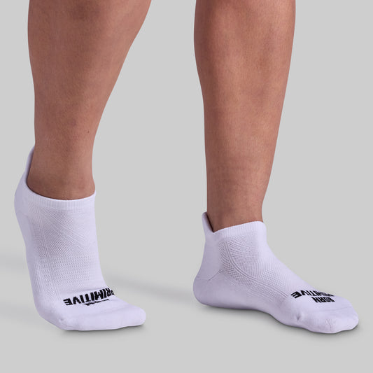 A pair of white ankle socks with black text on the side, worn on human feet against a light background.