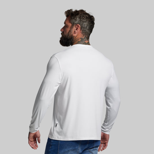 Man wearing a white long-sleeve shirt and blue jeans on a gray background
