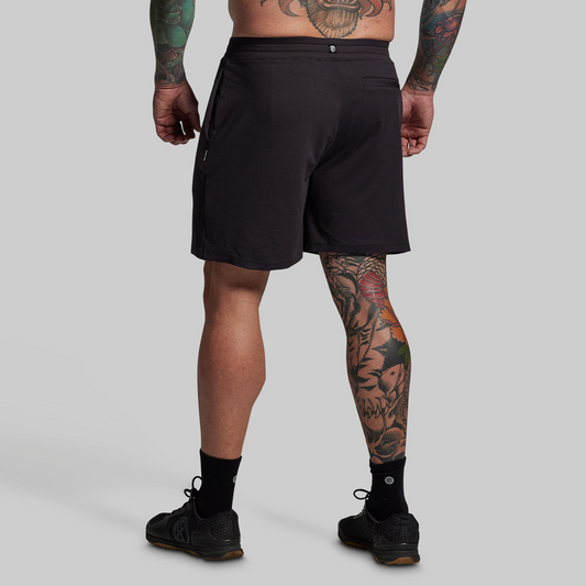 Person wearing black shorts on a plain background