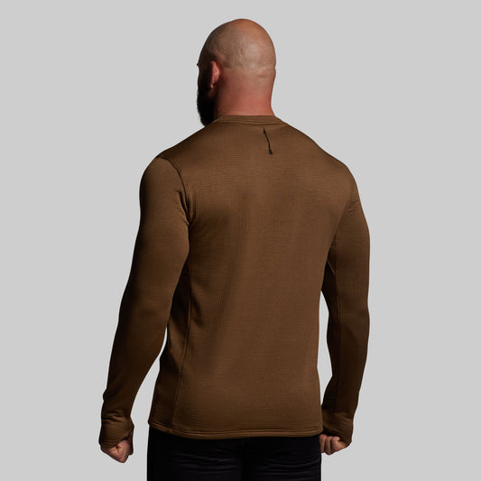 Man wearing a brown long-sleeve shirt against a gray background
