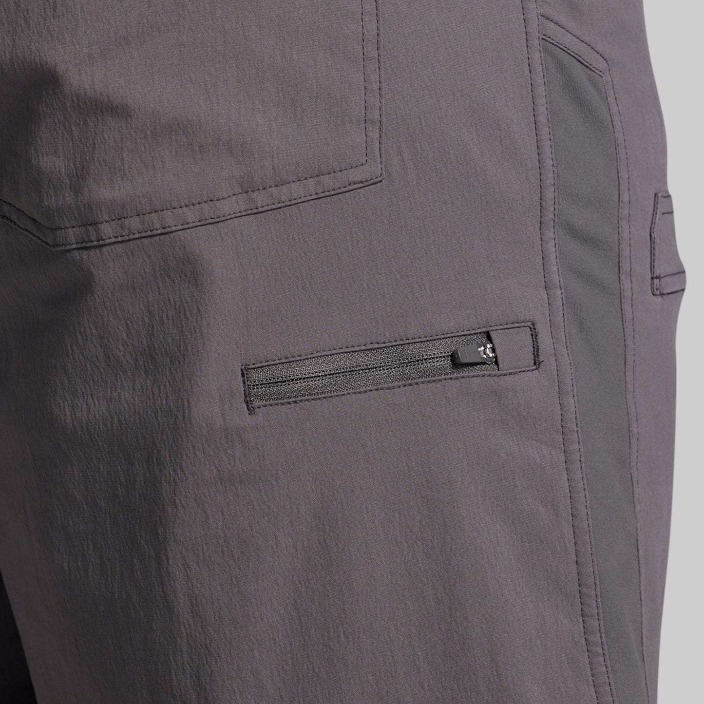 Close-up of gray shorts with a zipper pocket on a plain background