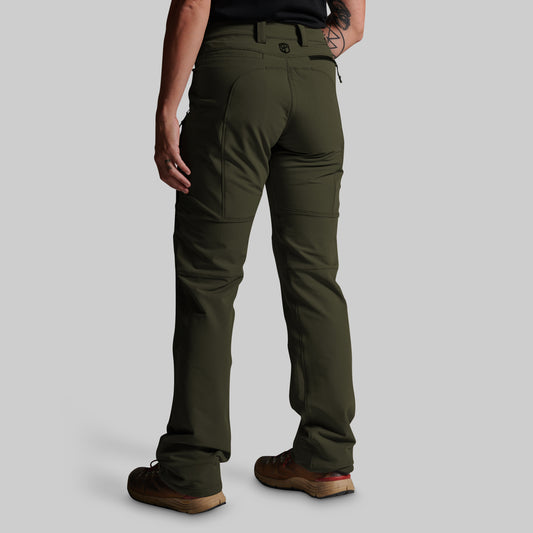 A person shown from the back wearing olive green pants, a black top, and brown shoes against a light gray studio background.