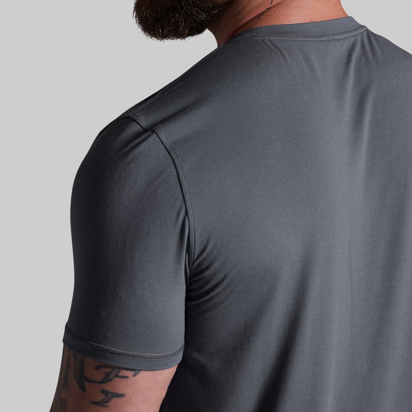 Gray athletic shirt worn by a person on a light gray background