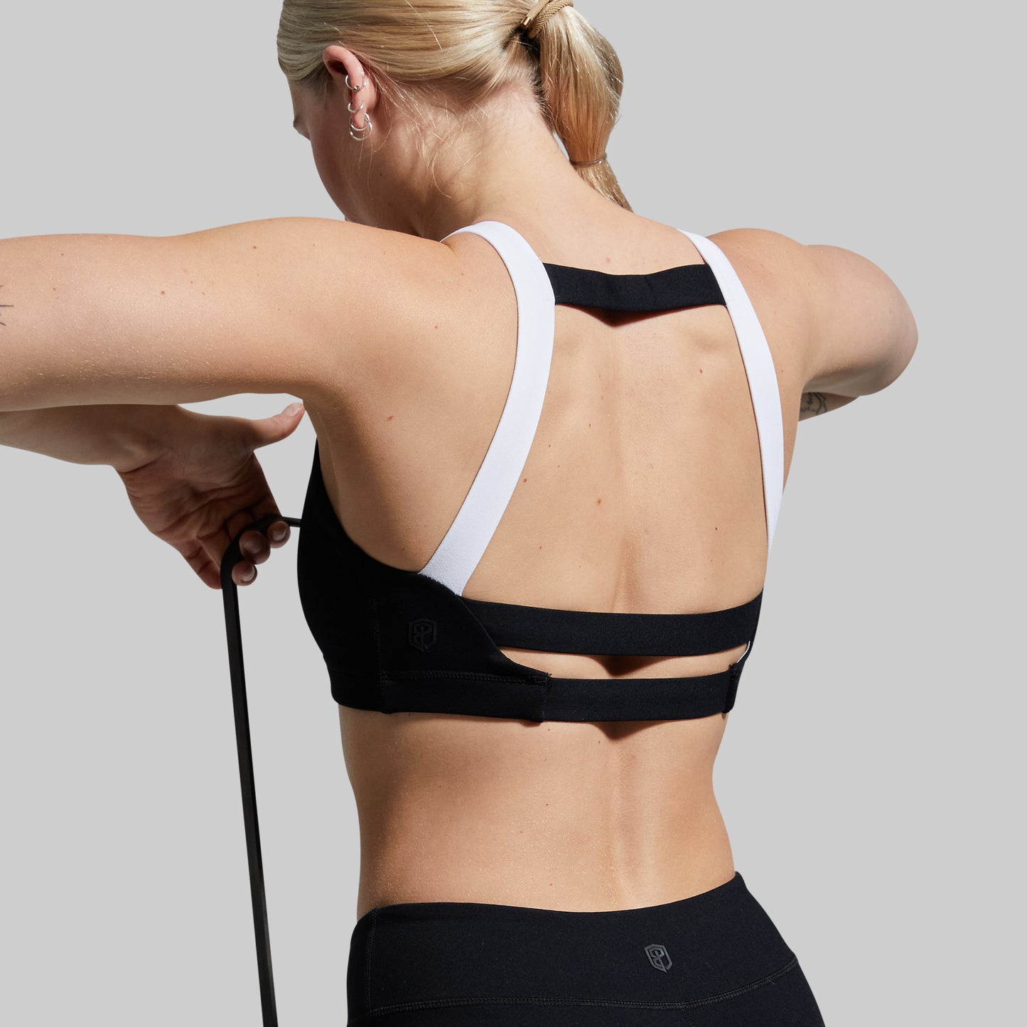 Person wearing a black and white sports bra with a gray background