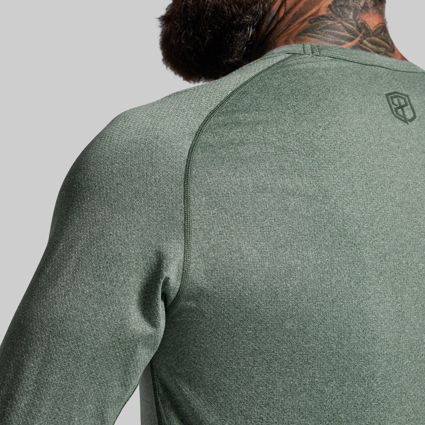 Person wearing a green athletic shirt with a brand logo on a gray background
