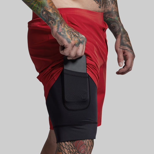 Person wearing red shorts with black compression shorts on a gray background