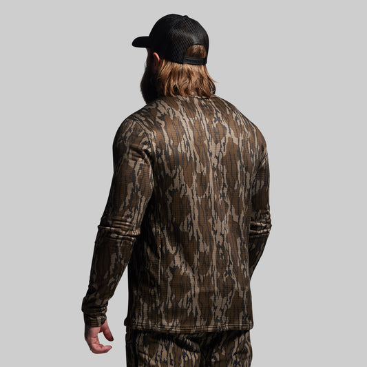 Person wearing a camouflage outfit with a cap on a gray background