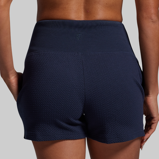 Navy blue textured shorts worn by a person on a gray background