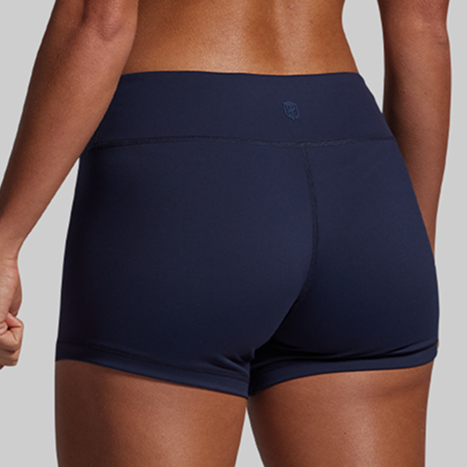Navy blue athletic shorts worn by a person on a gray background