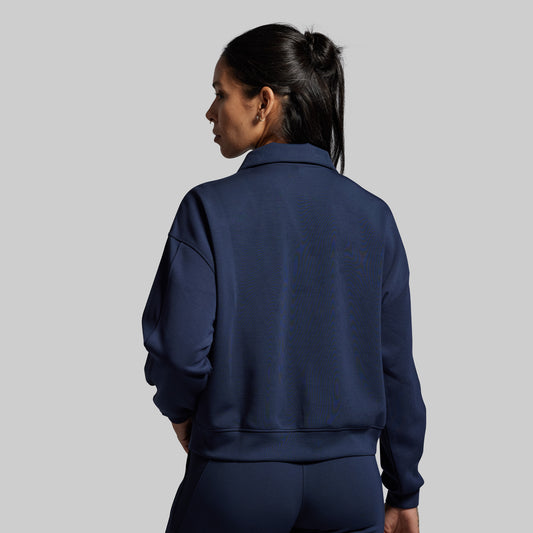 Person wearing a navy blue tracksuit against a gray background