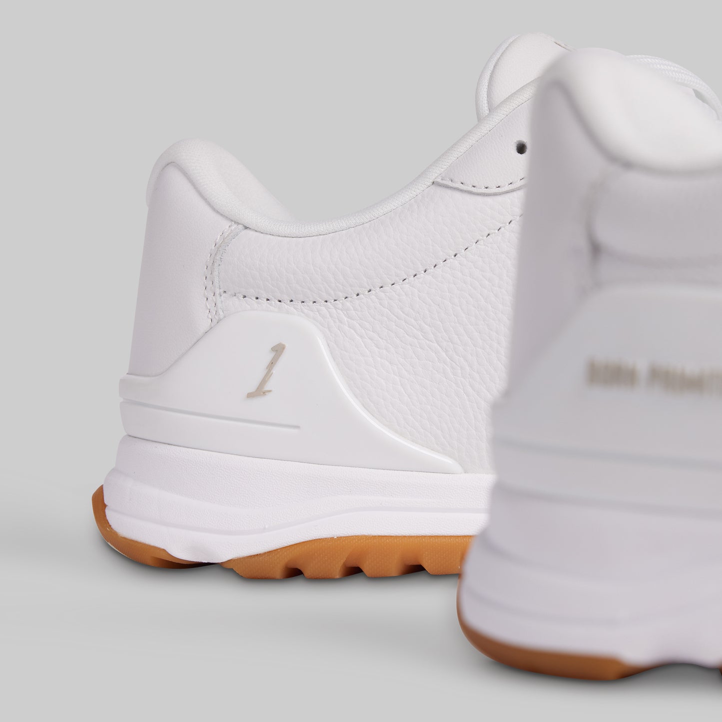 White sneakers with brown soles on a light gray background