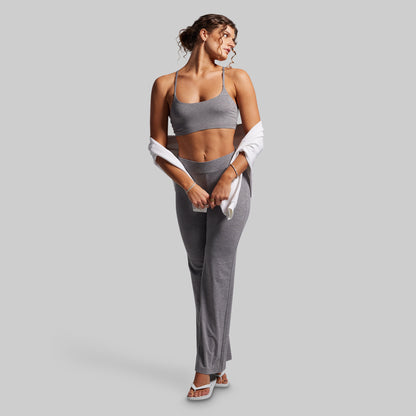 Woman in gray athletic wear holding a white sweatshirt on a light gray background