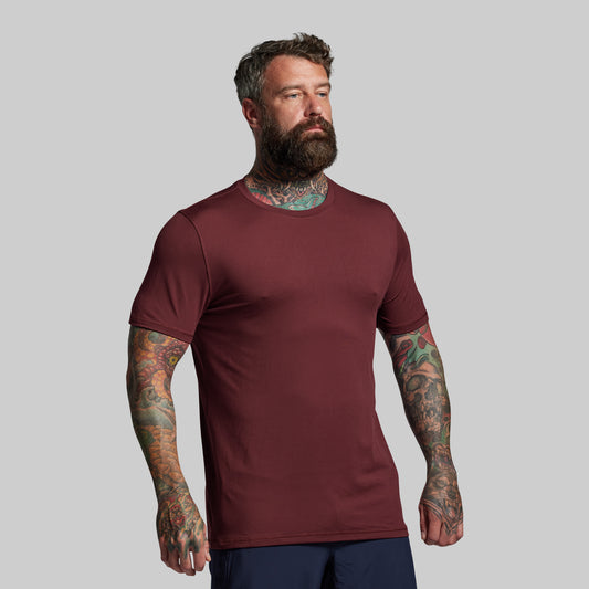 Man wearing a maroon t-shirt against a gray background