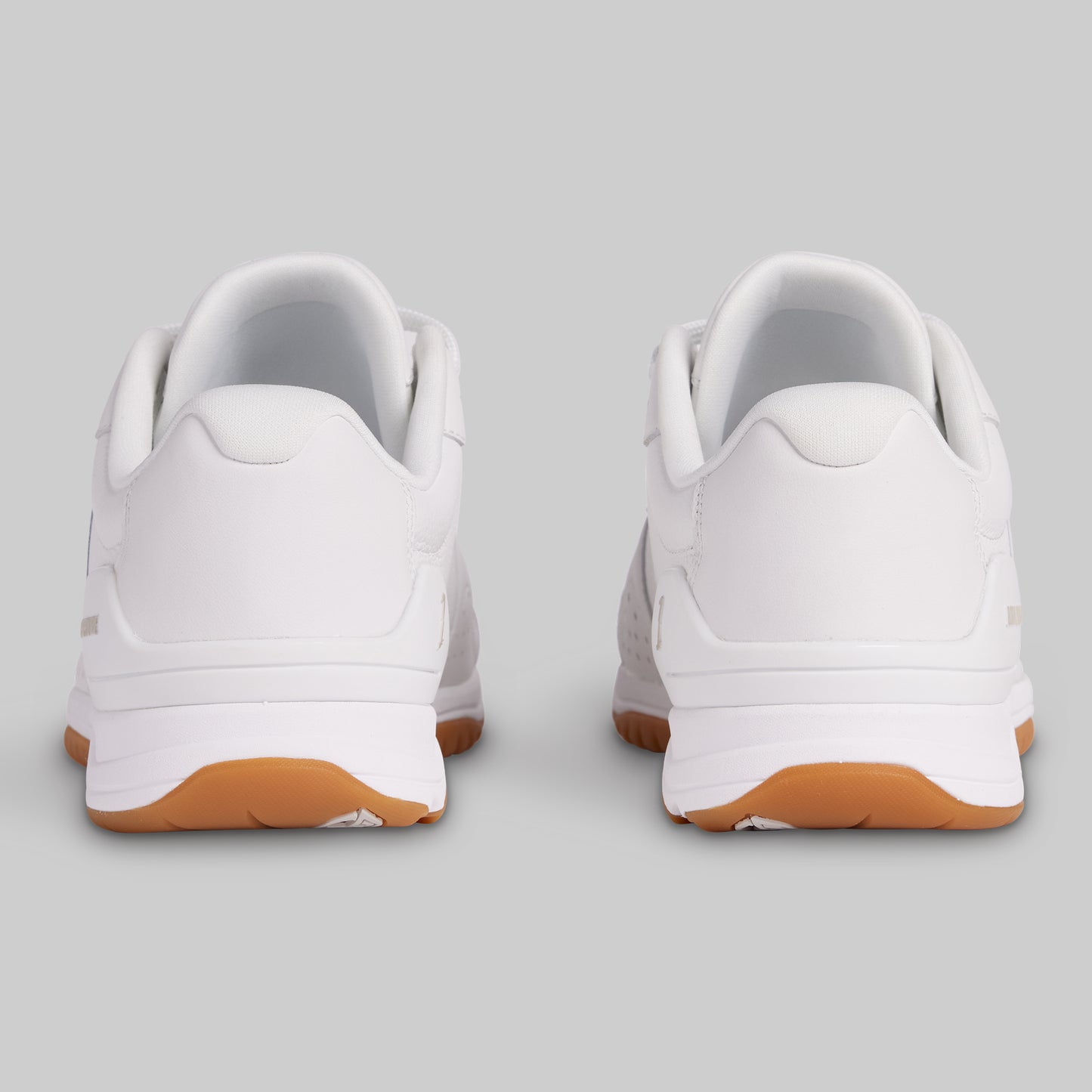 White sneakers with brown soles on a light gray background