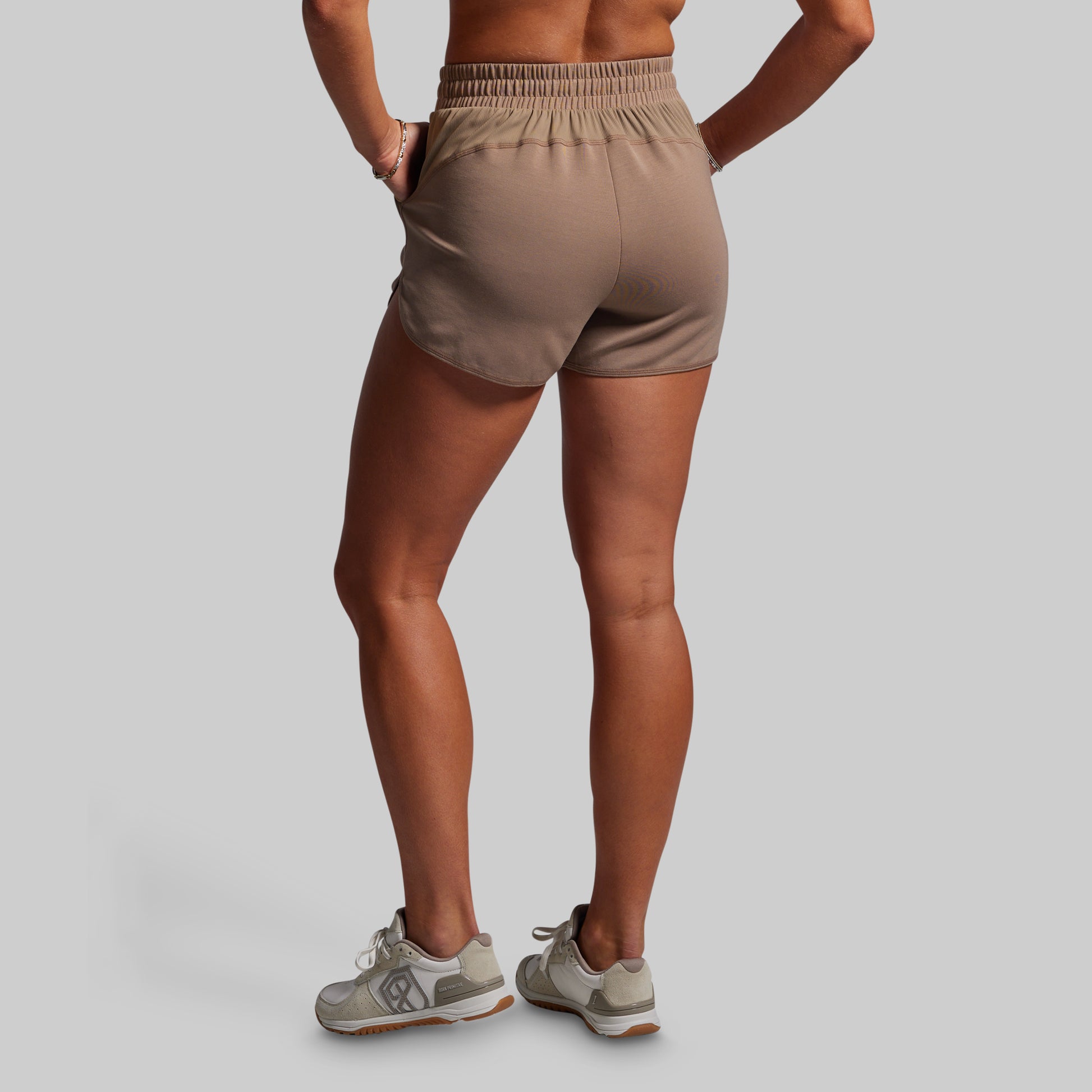 Person wearing beige athletic shorts on a plain background