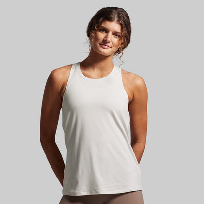 Woman wearing a white tank top against a plain background