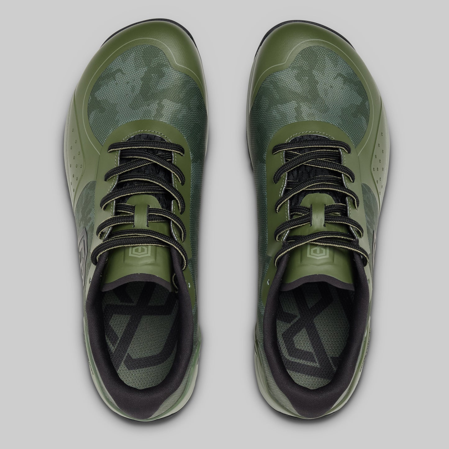 Pair of green athletic shoes with black accents on a light gray background