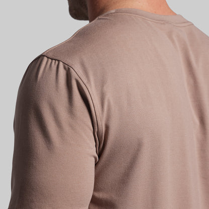 Close-up of a person wearing a brown shirt against a light gray background