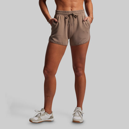 Person wearing beige shorts on a plain background