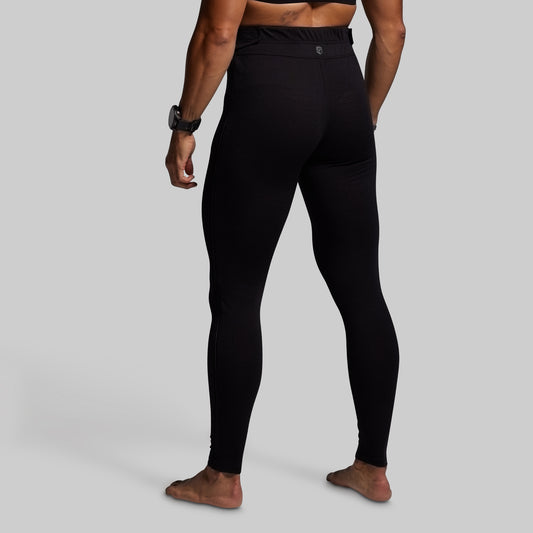 Person wearing black base layer bottoms on a gray background
