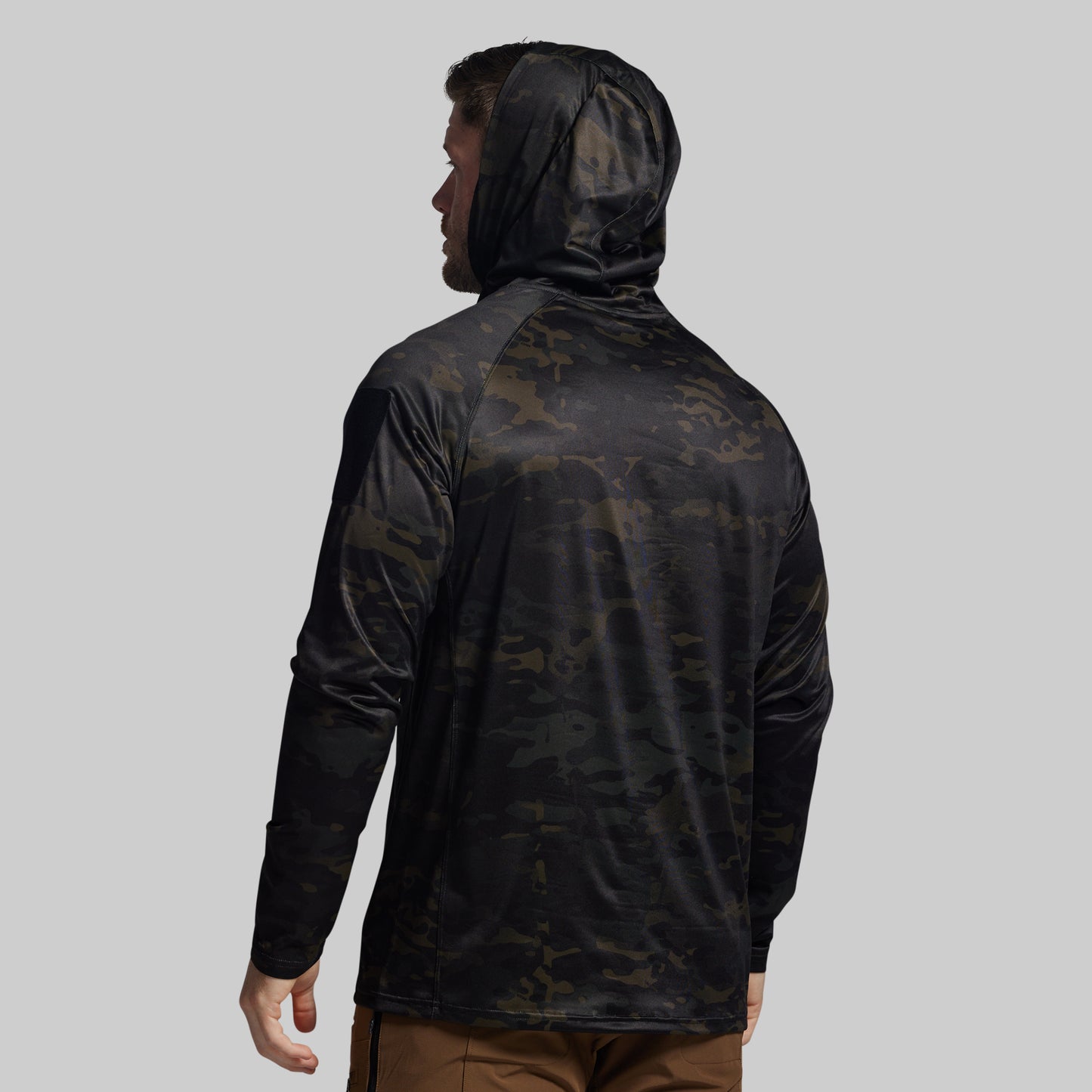 Person wearing a black camouflage hooded sun shirt on a gray background