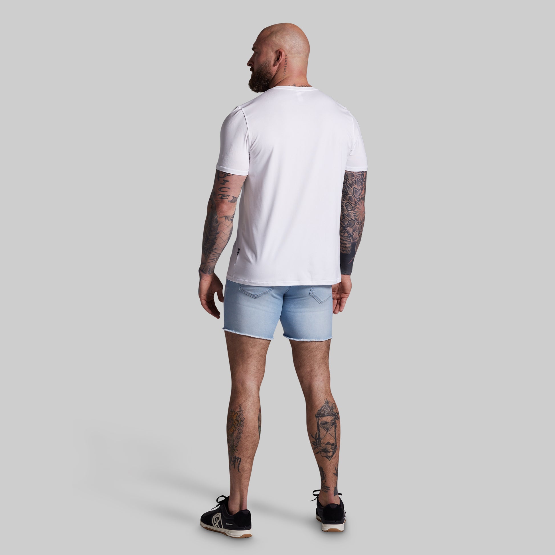 Man wearing a white t-shirt and light blue shorts on a gray background