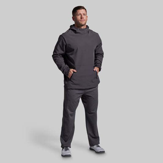 Man wearing a dark gray hoodie and pants on a light gray background