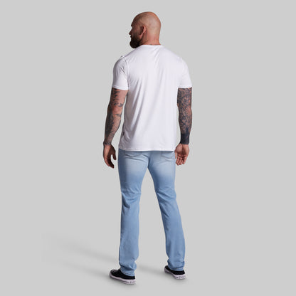 Man wearing a white t-shirt and light blue jeans on a gray background