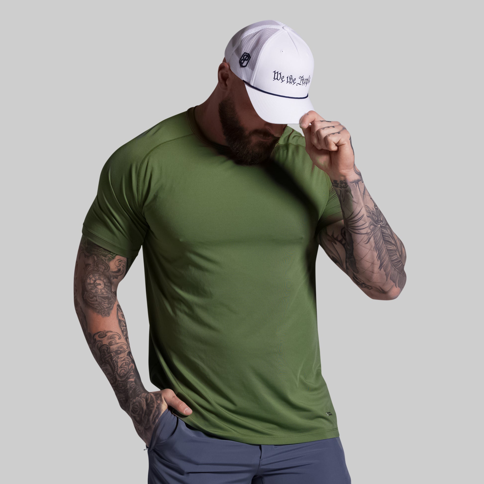 Man wearing a green t-shirt and white cap with text on a gray background