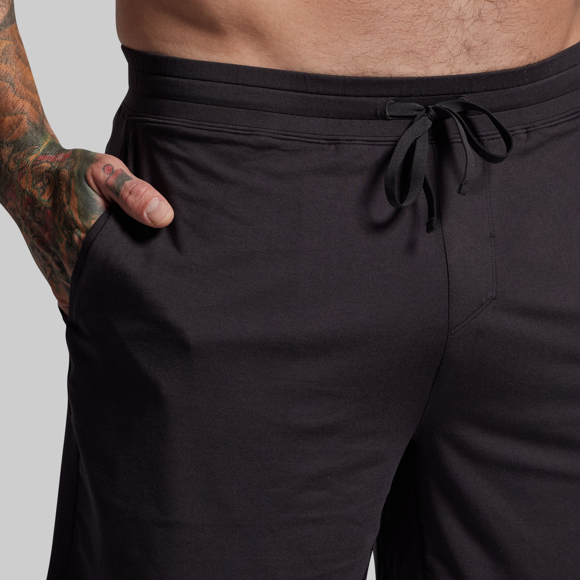 Black shorts with a drawstring waistband on a plain background