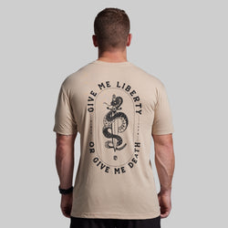 Man wearing a beige t-shirt with a snake and text design on the back against a gray background