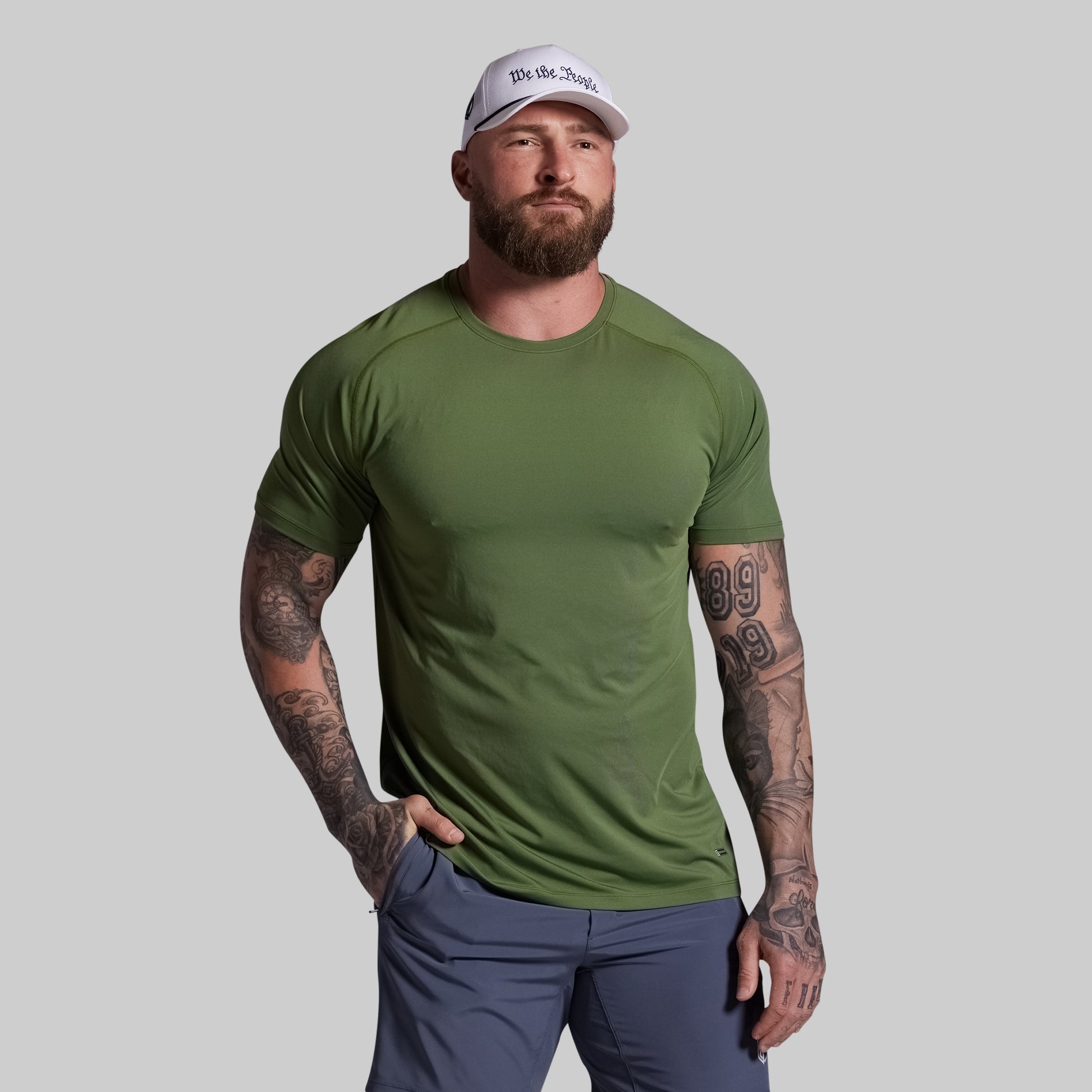 Man wearing a green t-shirt and white cap on a gray background