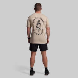 Man wearing a beige t-shirt with a graphic design and text on the back, standing against a plain background.