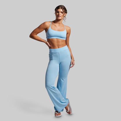 Woman wearing a light blue sports bra and high-waisted wide-leg pants on a gray background