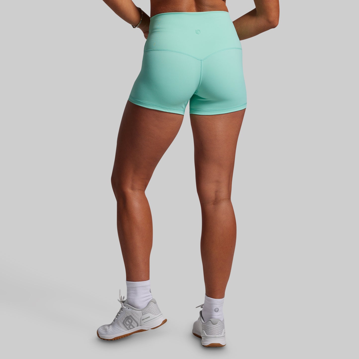Person wearing teal athletic shorts on a gray background