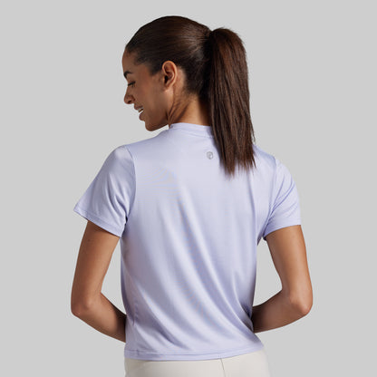 A woman with her hair in a ponytail is shown from the back wearing a light lavender short-sleeve athletic t-shirt. 